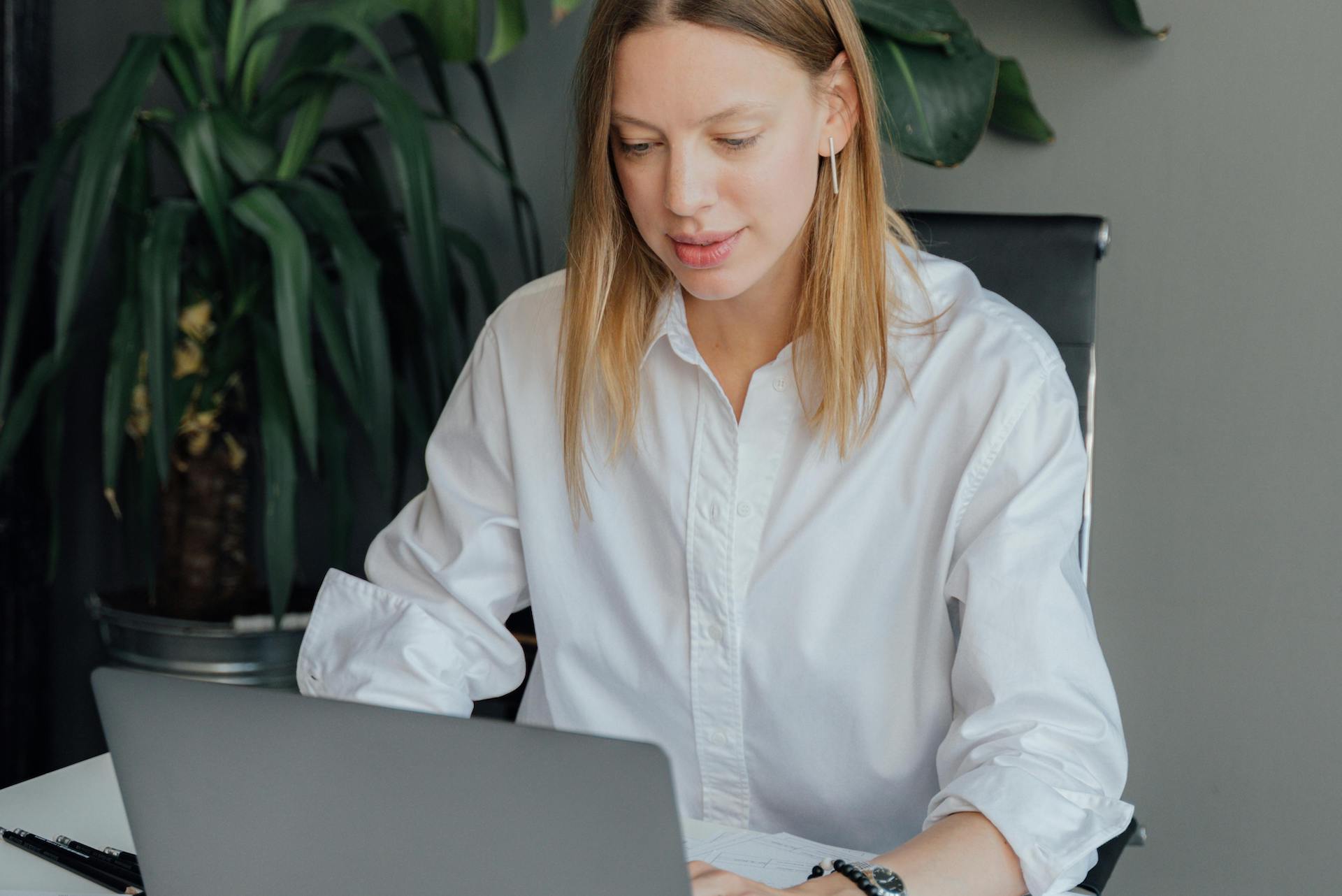 Blonde woman sitting at a desk working on a laptop